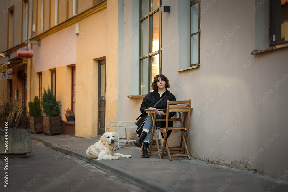 Cute funny girl portrait with her golden dog on street
