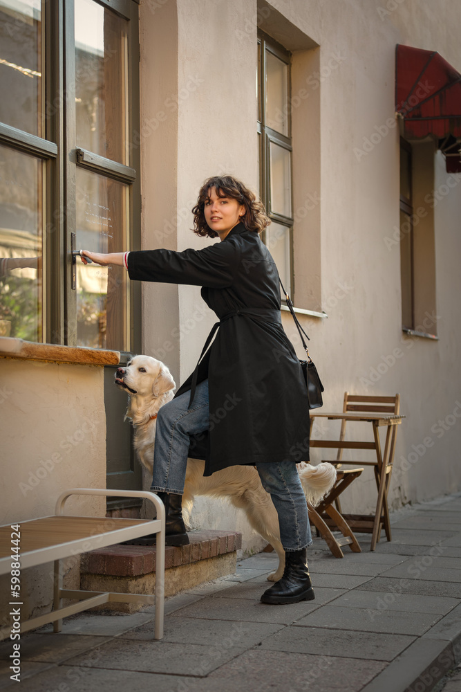 Cute funny girl portrait with her golden dog on street