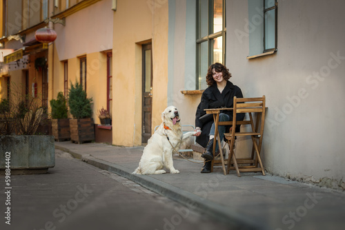 Cute funny girl portrait with her golden dog on street