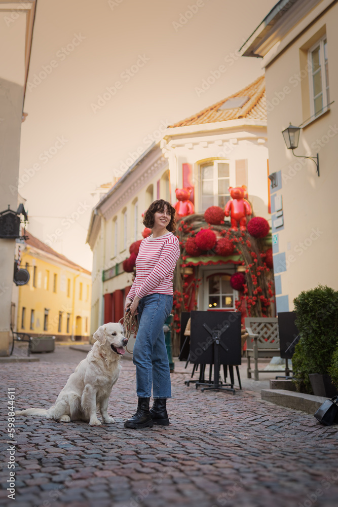 Cute funny girl portrait with her golden dog on street
