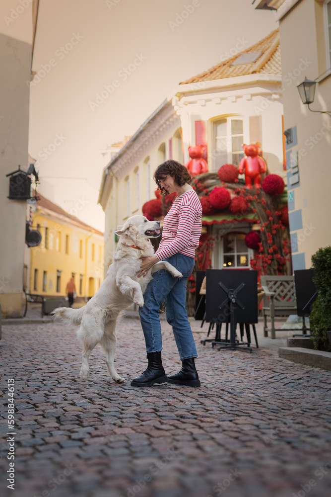 Cute funny girl portrait with her golden dog on street