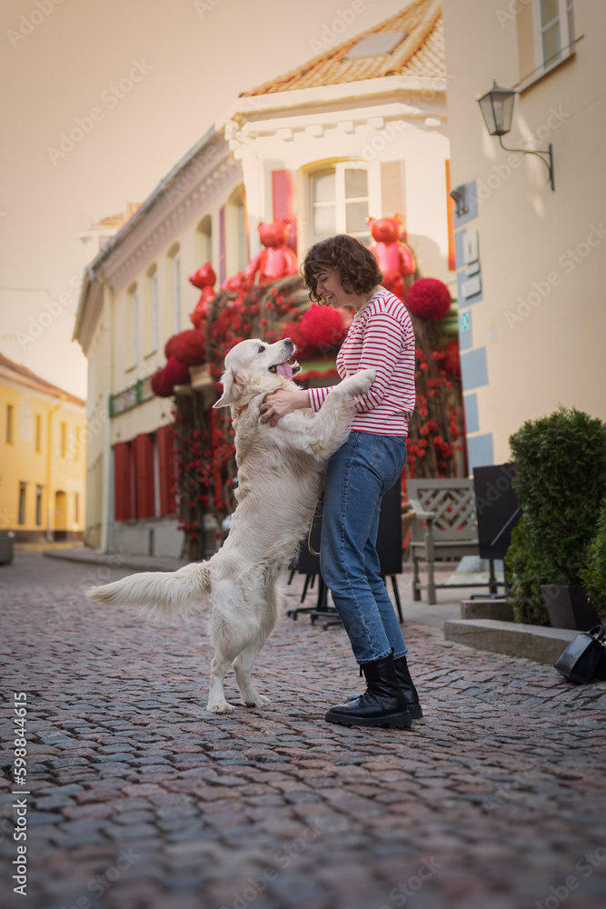 Cute funny girl portrait with her golden dog on street