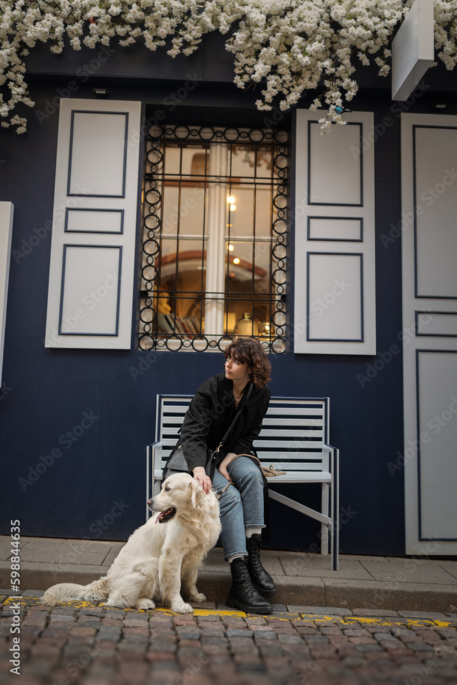 Cute funny girl portrait with her golden dog on street