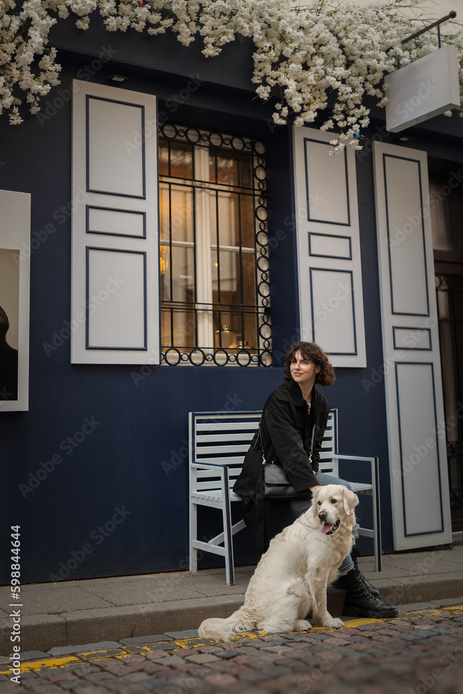 Cute funny girl portrait with her golden dog on street
