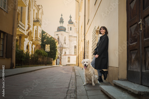 Cute funny girl portrait with her golden dog on street
