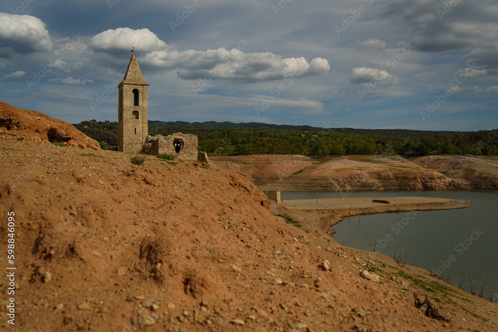 Vilanova de Sau, Spain - 28 April 2023: The bell tower of Sant Romà de Sau is seen at the Sau reservoir as the drought caused by climate change causes water shortages in Spain and Europe.