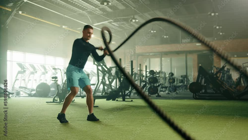 Grappler toss exercise on battle rope done by athletic young handsome
