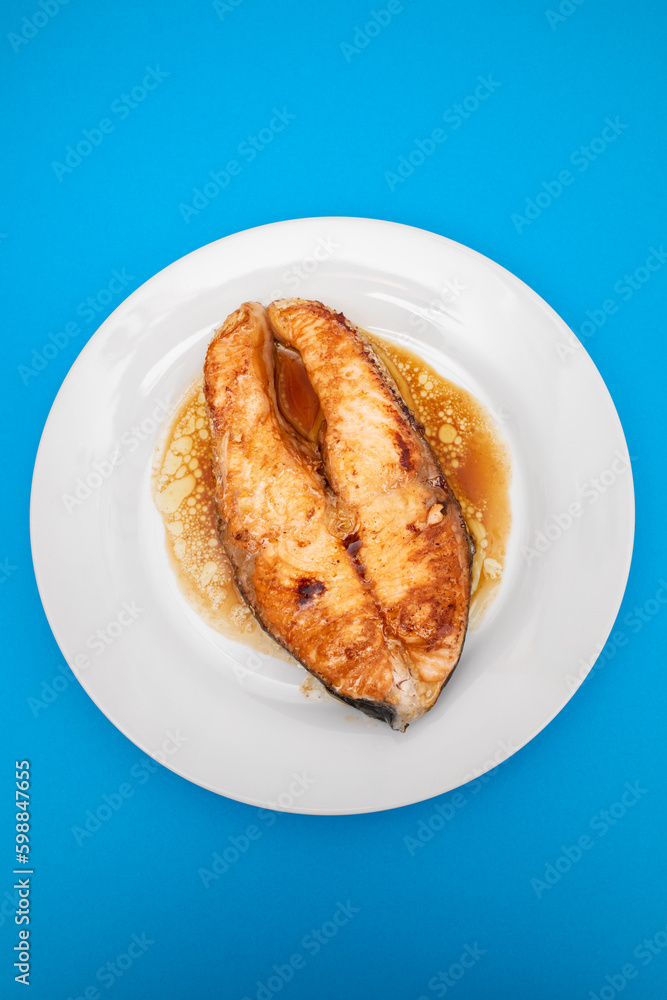 Fried salmon steak with sauce on white dish Fried salmon steak with sauce on white dish