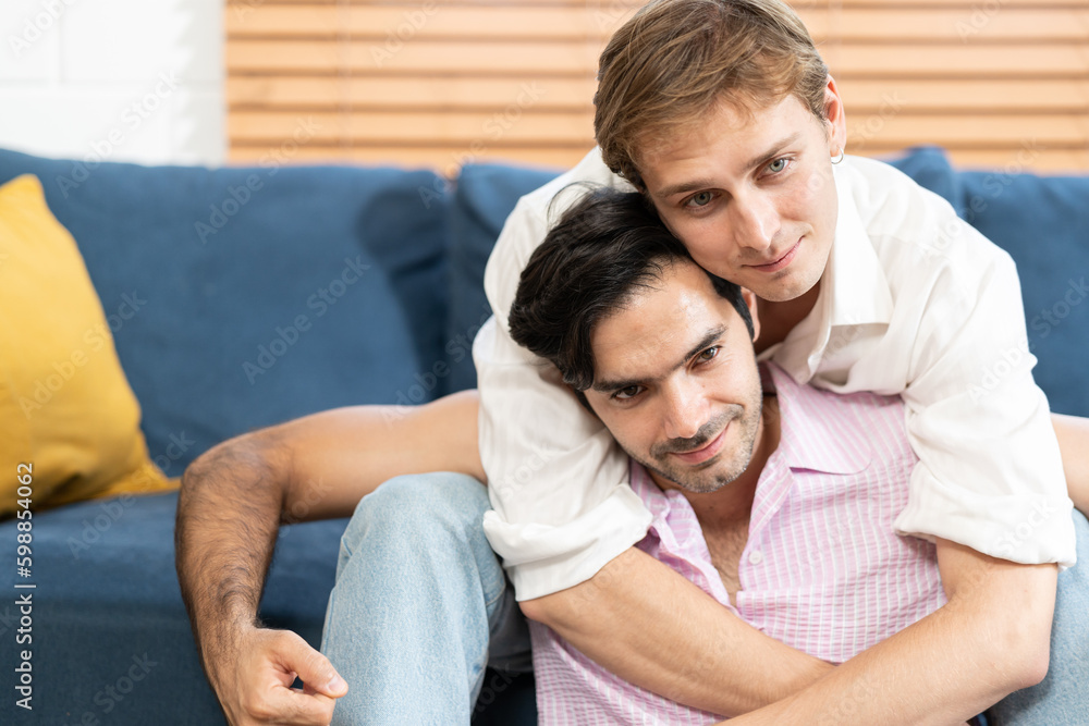 Gay Couple Sit Together on a Sofa at Home. Boyfriends are Hugging and Embracing Each Other. A gay couple hug each other. Gay Couple Sit Together on a Sofa at Home. Boyfriends are Hugging and Embracing Each Other. A gay couple hug each other.