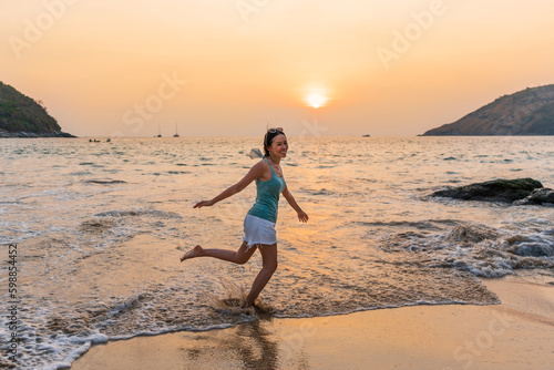 Happy young Asian woman enjoy the moment of sunrise or sunset at the beach. Summer  vacation and holiday concept. Copy space