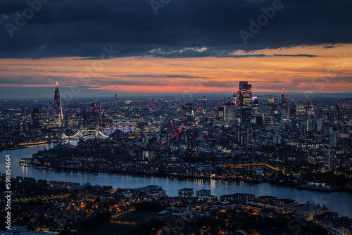 Wide aerial panorama of the illuminated London skyline during evening, England, with River Thames leading into the city © moofushi