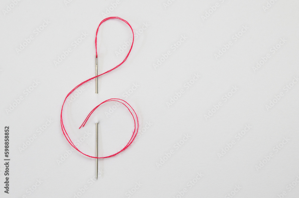 Red cord through the Needle In The Form Of A Treble Clef Red cord through the Needle In The Form Of A Treble Clef