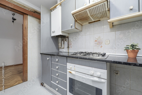 An old and very used kitchen with gray furniture and appliances that were once white