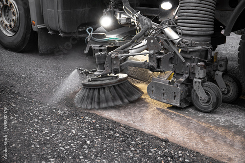 Close up view of heavy duty street cleaning vacuum machine known as street sweeper brushing the streets clean. photo