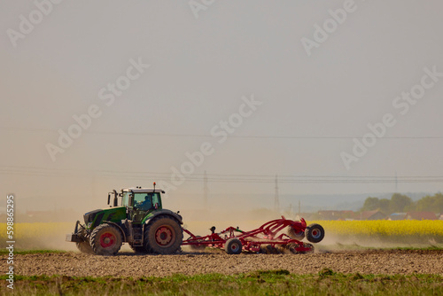 a tractor in an agricultural field shredding the earth on a hot day