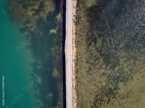 Road passing through the lake. Travel and explore concept. Road in between water. Aerial drone view.