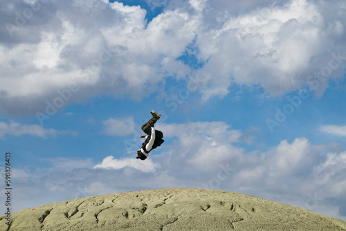 Man doing a backflip on mountain of on top of the mountain. black young dancer man somersaulting