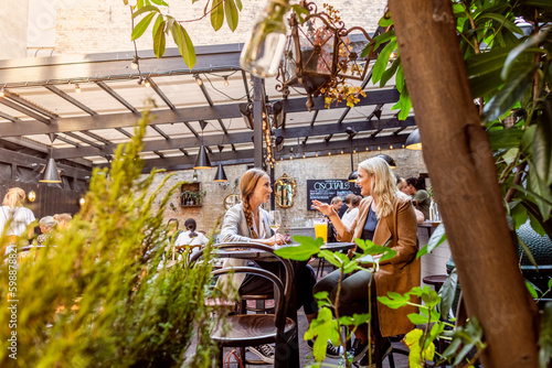 Two female friends relaxing in outdoor cafe