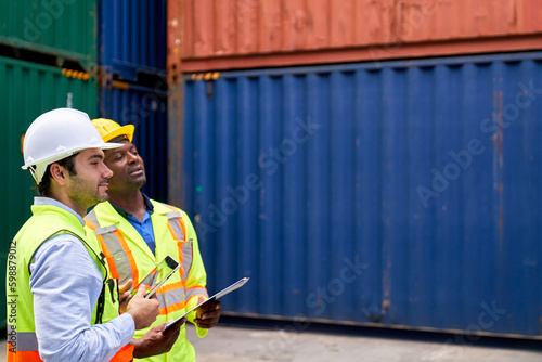 Team of foreman working with tablet and paper chart in logistic container box site