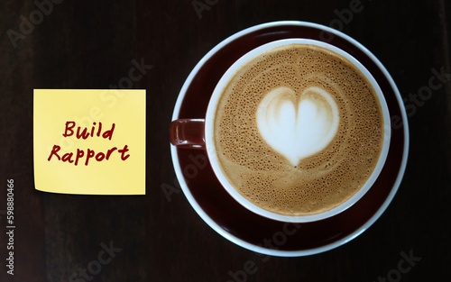Coffee cup with handwritten text note BUILD RAPPORT, to remind self to building relationships with others in which both parties feel supported and understood to accomplish career goals