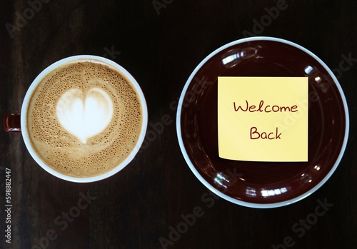 Coffee cup in cafe with text on sticky note WELCOME BACK, concept of business re-opening again after renovation or pandemic lockdown, welcome back greeting to customers, visitors or travellers
