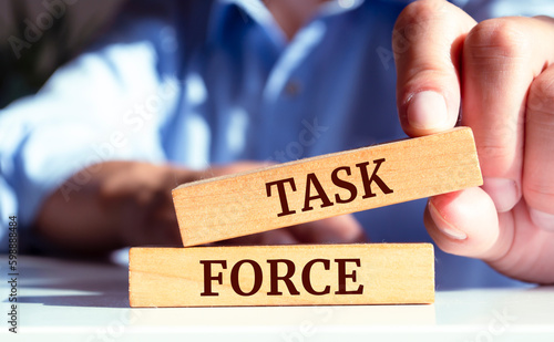 Close up on businessman holding a wooden block with a "Task force" message