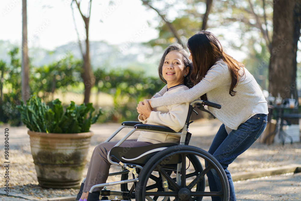Asian senior woman in wheelchair with happy daughter. Family relationship retired woman sitting on wheelchair in the park age care at retirement home. Asian senior woman in wheelchair with happy daughter. Family relationship retired woman sitting on wheelchair in the park age care at retirement home.