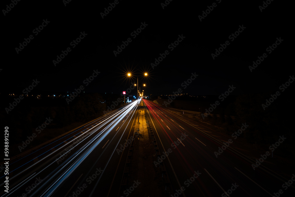 Flowing traffic and lengthening lights of vehicles on the highway at night. Long exposure
