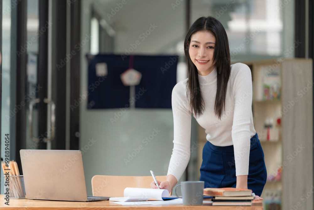 Portrait of a beautiful smiling businesswoman standing at her desk. Portrait of a beautiful smiling businesswoman standing at her desk.