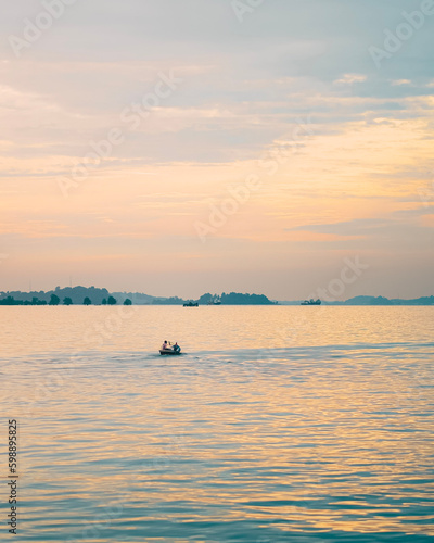 Silhouette of a small boat sailing into the twilight at Batam Harbor
