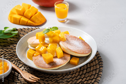 Fototapeta Naklejka Na Ścianę i Meble -  Delicious Japanese souffle pancake with dice mango and jam on gray table background.