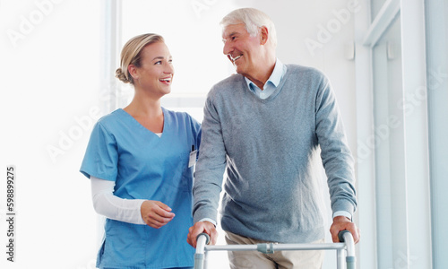 Learning to walk with great support. a senior man using a walker with the assistance of a young nurse.