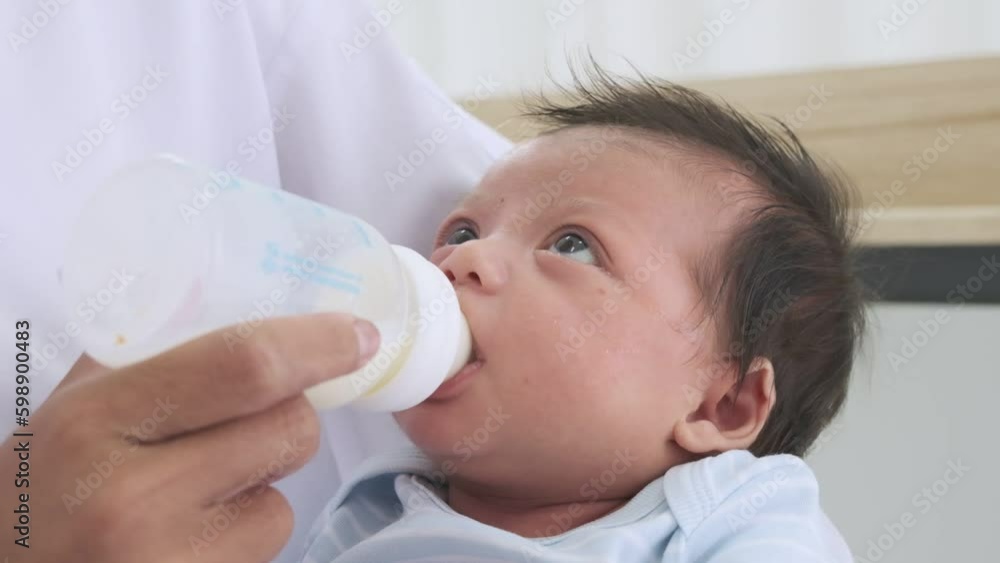 Mother holding her baby and feeding her baby with a milk bottle on the bed. Mother holding her baby and feeding her baby with a milk bottle on the bed.