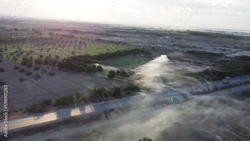 Aerial drone backward moving shot over RCD road in Baluchistan surrounded by agricultural farmlands during morning time. White fog. photo