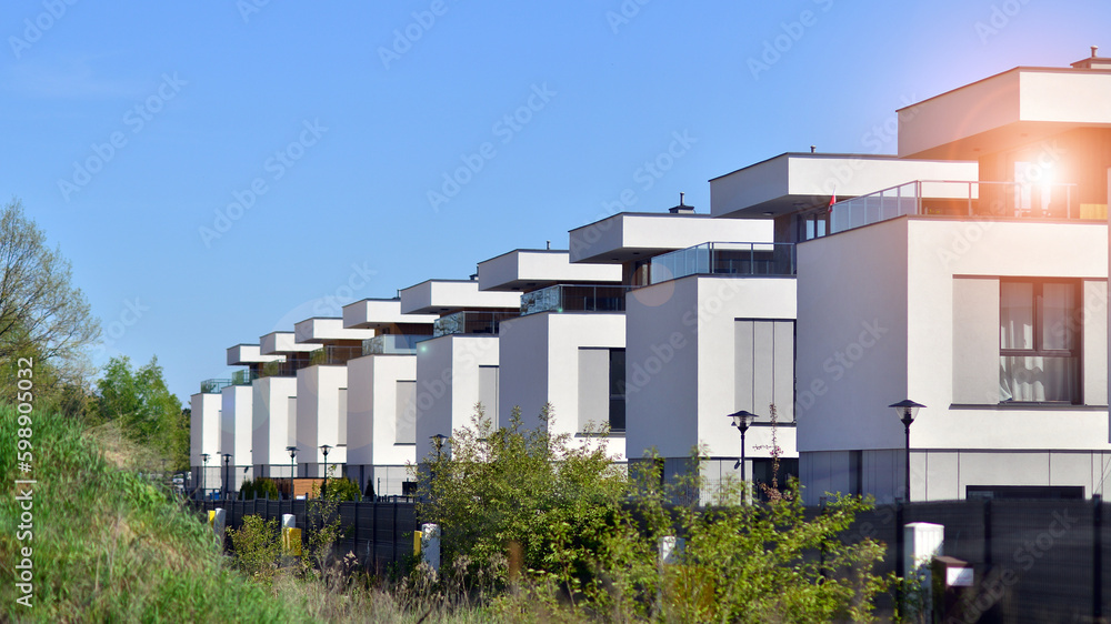 Terraced family homes in newly developed housing estate. The real estate market in the suburbs. New single family houses in a new development area. Residential homes with modern facade.  - obrazy, fototapety, plakaty 