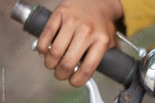 A hand holds the handle and brake of a bicycle and the background is blurred