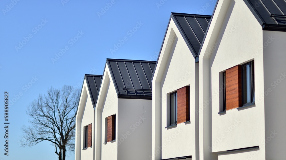 Terraced family homes in newly developed housing estate. The real estate market in the suburbs. New single family houses in a new development area. Residential homes with modern facade. Terraced family homes in newly developed housing estate. The real estate market in the suburbs. New single family houses in a new development area. Residential homes with modern facade.