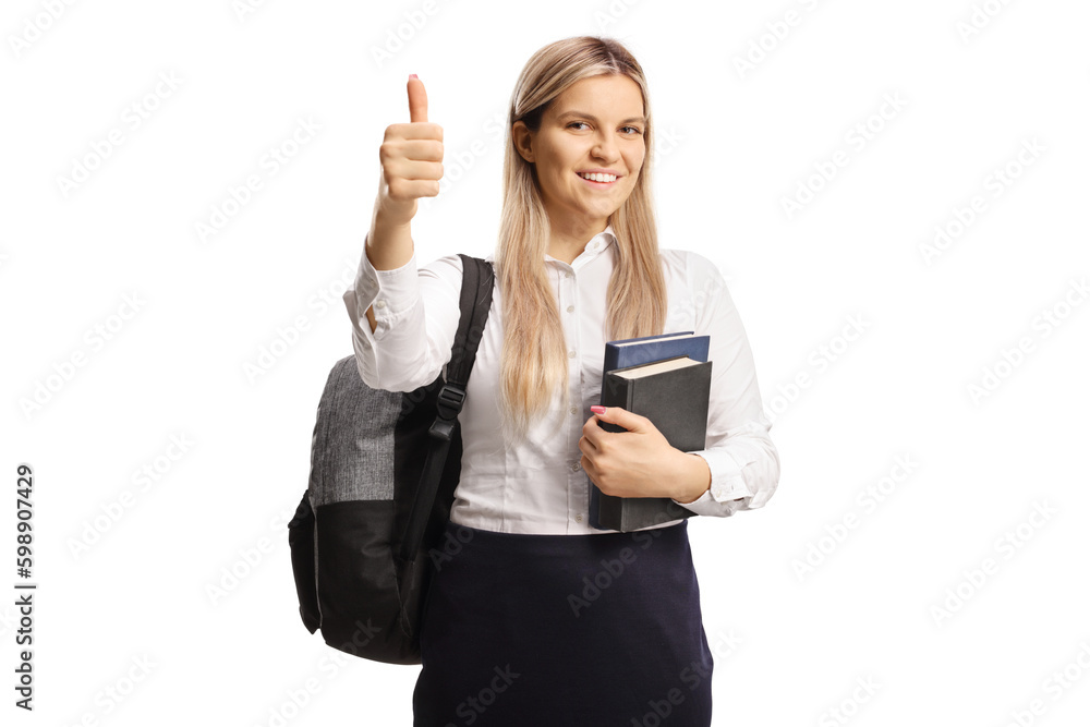 Cheeful female student holding books and showing a thumb up sign Cheeful female student holding books and showing a thumb up sign