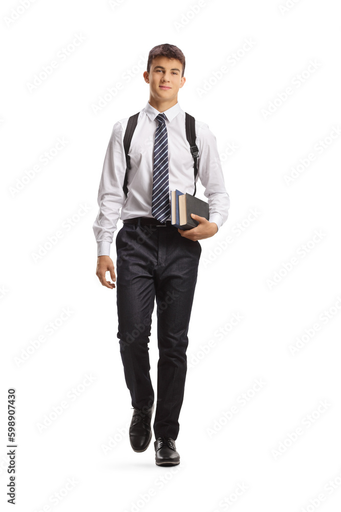 Full length portrait of a male student carrying books and walking towards camera Full length portrait of a male student carrying books and walking towards camera