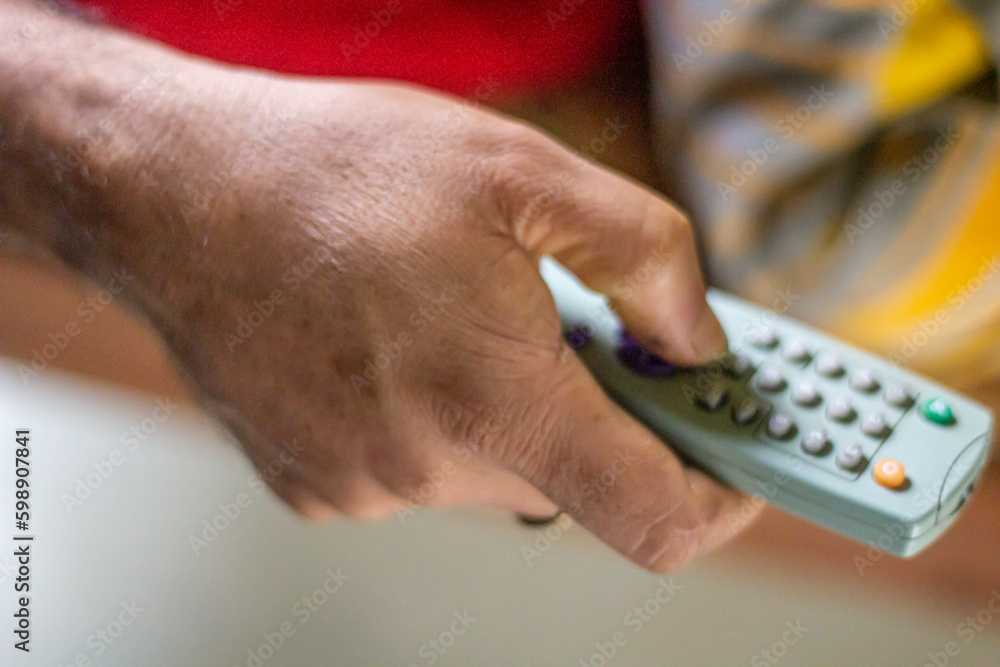 A hand holds a remote and the background is blurred A hand holds a remote and the background is blurred