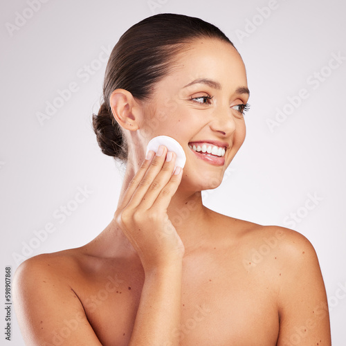 Unclogged pores keeps the skin glowing. an attractive young woman wiping her face with cotton against a studio background.