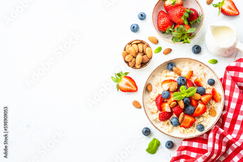 Oatmeal porrige with fresh berries and nuts. Healthy breakfast, top view.