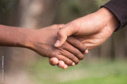 Two hands are holding the handshake together and the background is blurred © Rokonuzzamnan