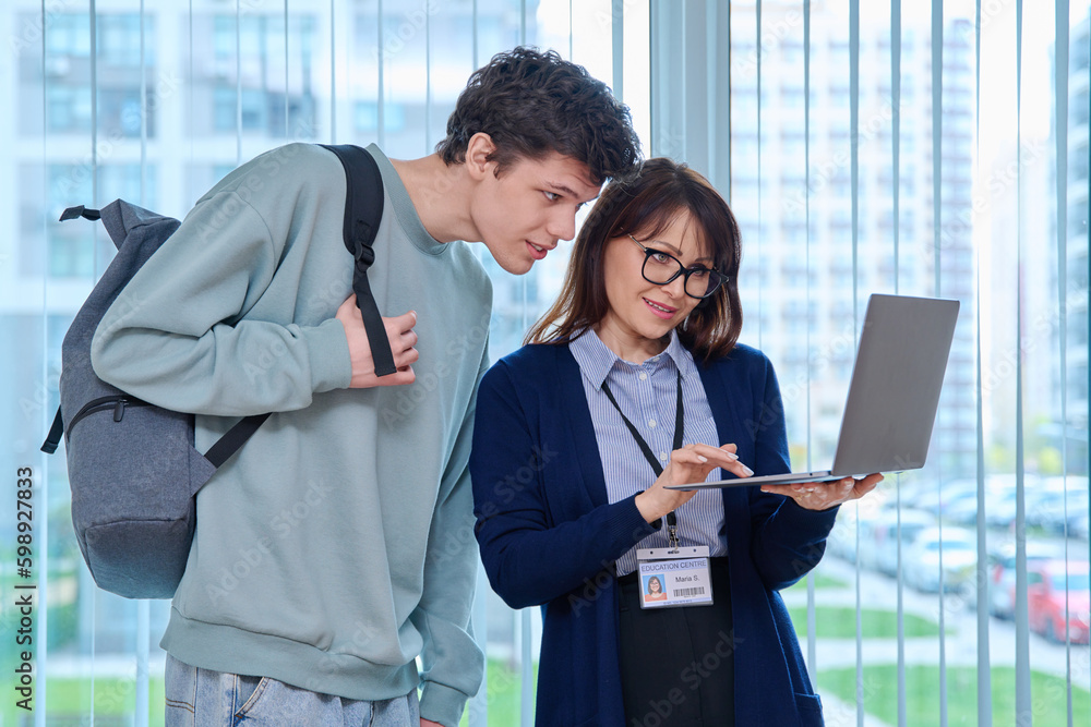 Female teacher and guy college student looking at laptop screen Female teacher and guy college student looking at laptop screen