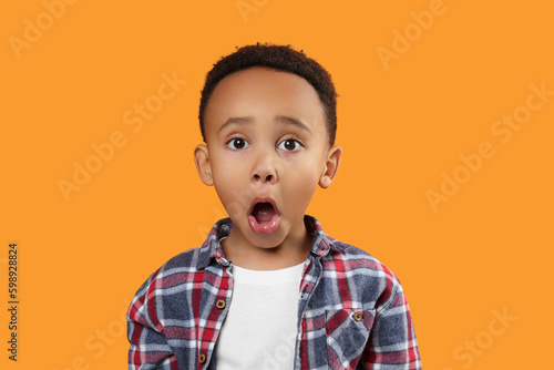 Portrait of emotional African-American boy on orange background