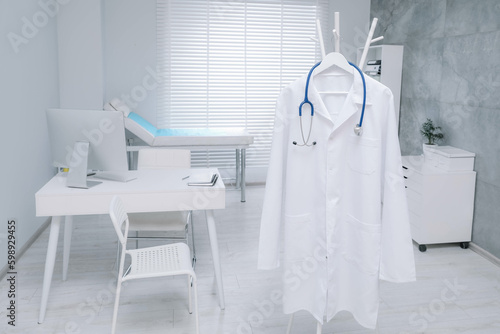 White doctor's gown and stethoscope hanging on rack in clinic © New Africa