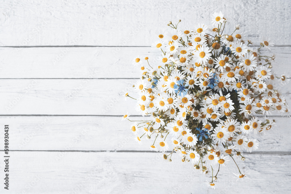 Bouquet of chamomiles on an old white wooden board, top view, copy space. Floral vintage background with wildflowers - obrazy, fototapety, plakaty 