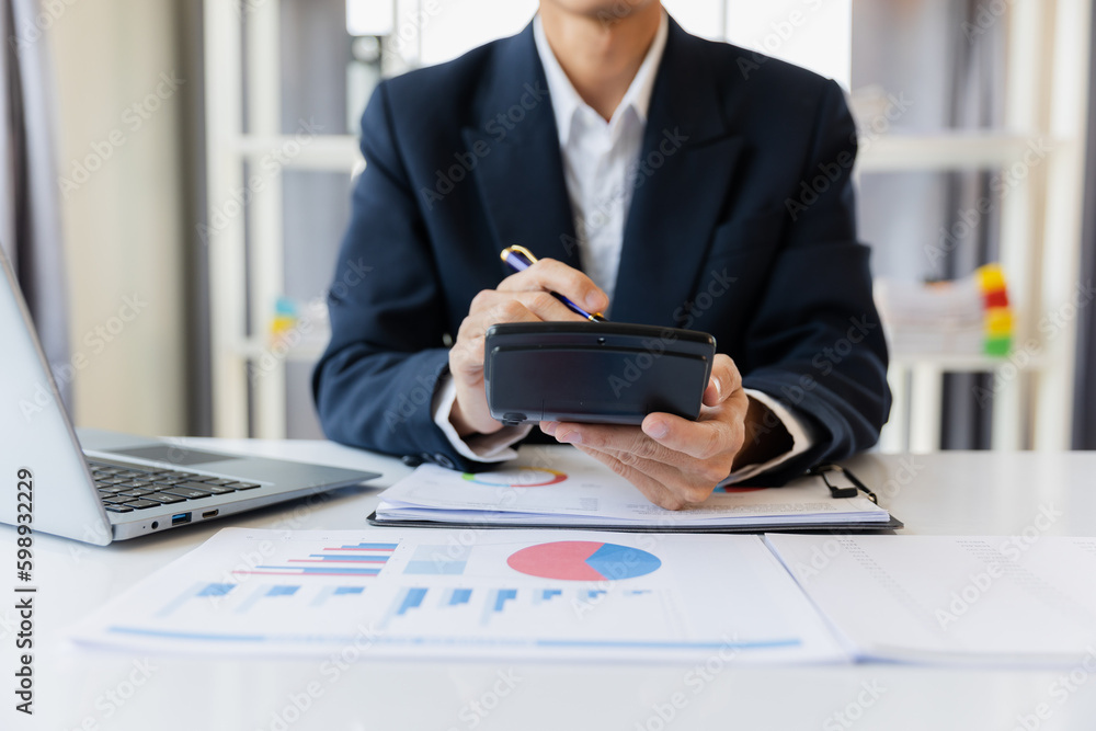 Asian businessman working at office with laptop, tablet and graph data sheet on his desk. Asian businessman working at office with laptop, tablet and graph data sheet on his desk.