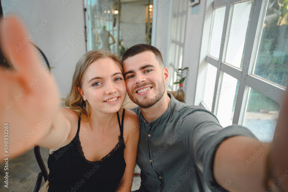 A young couple with a comfortable lifestyle. Young couple looking at selfie camera Two Caucasian couple taking a selfie on their phone