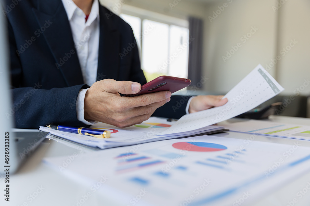 Asian businessman working at office with laptop, tablet and graph data sheet on his desk. Asian businessman working at office with laptop, tablet and graph data sheet on his desk.